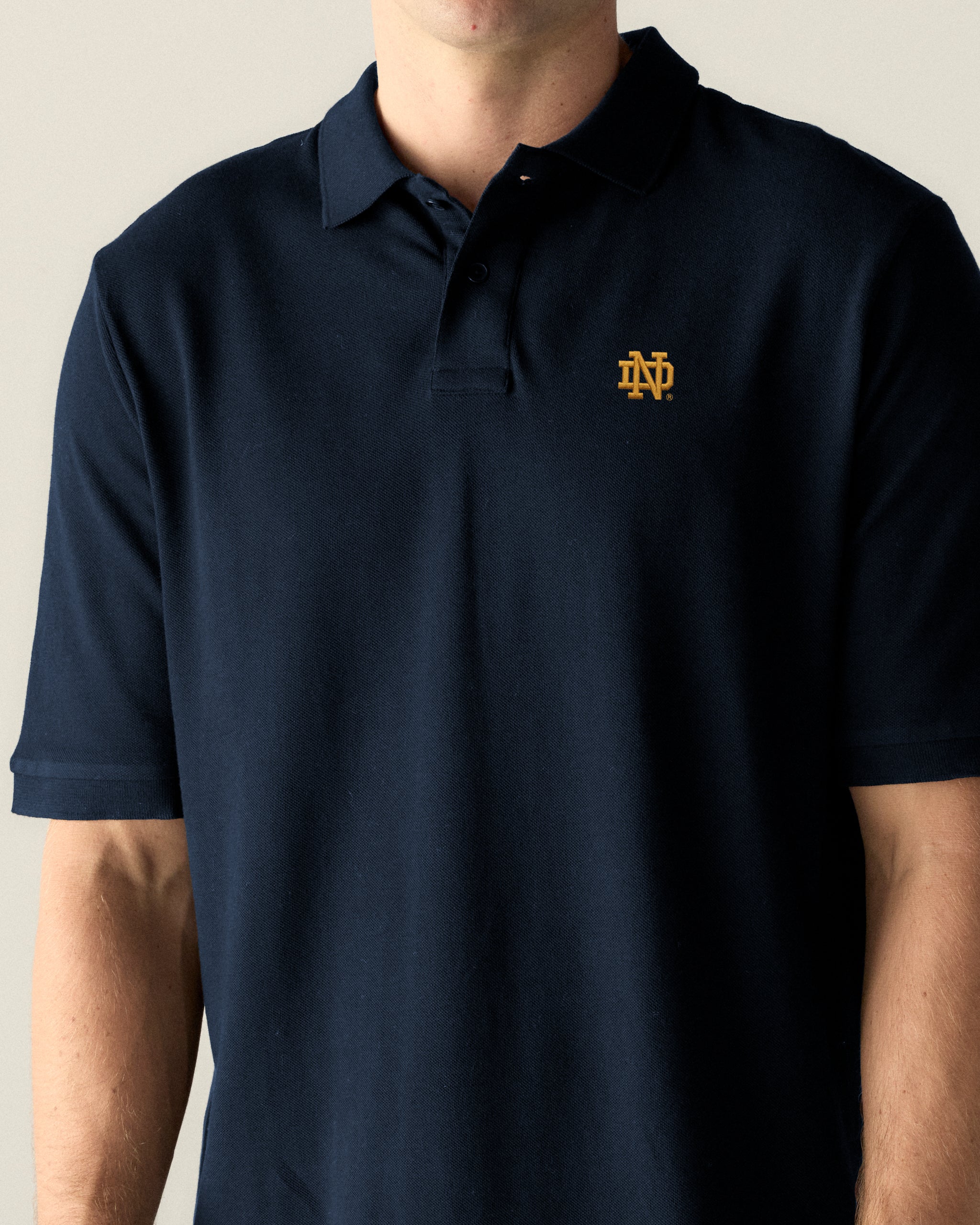 Navy pique polo shirt with gold collegiate logo, short sleeves, classic fit. Class Trip | Officially Licensed Collegiate Apparel