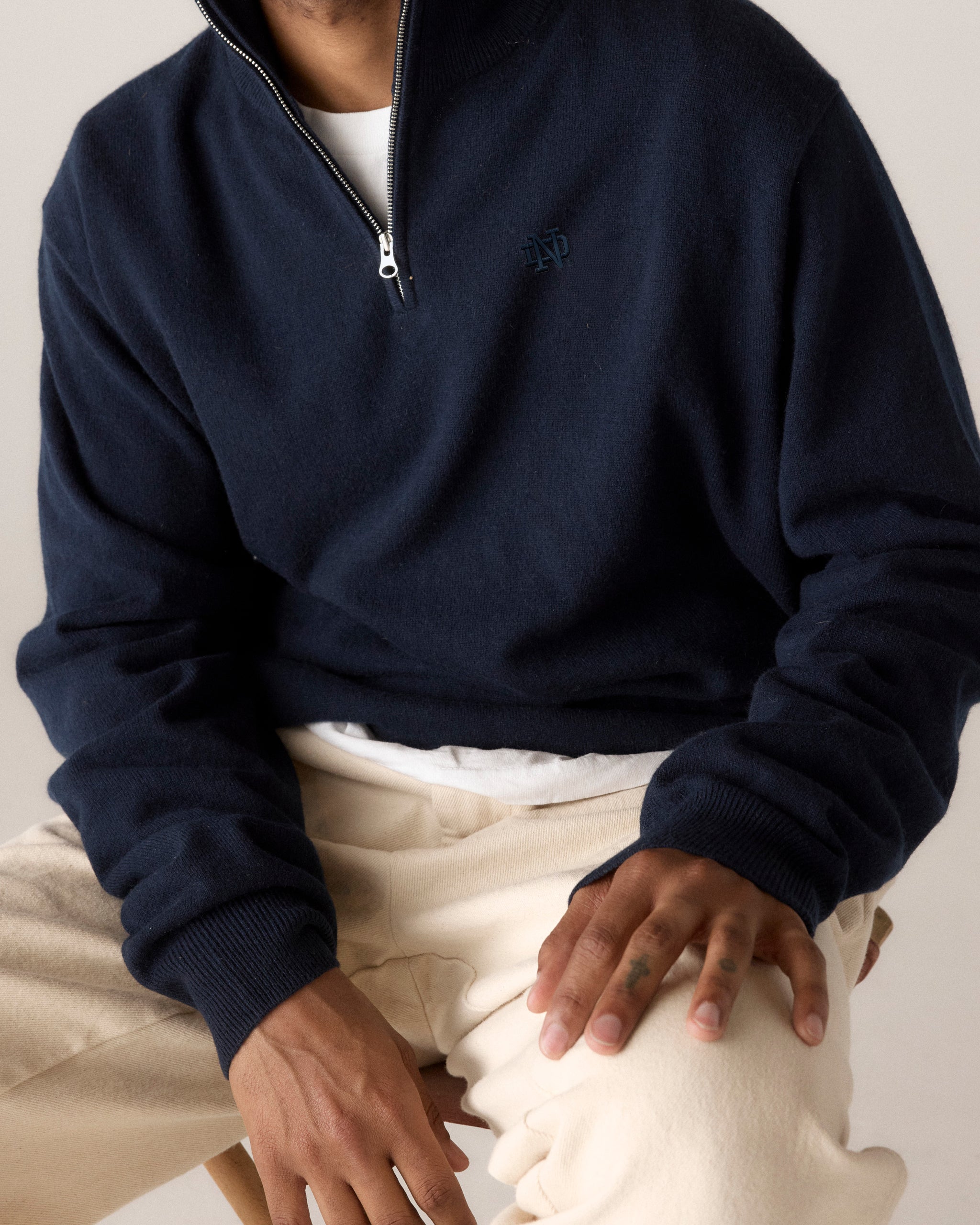 Navy blue quarter-zip pullover with ND logo, layered over white tee, paired with cream pants. Class Trip | Officially Licensed Collegiate Apparel