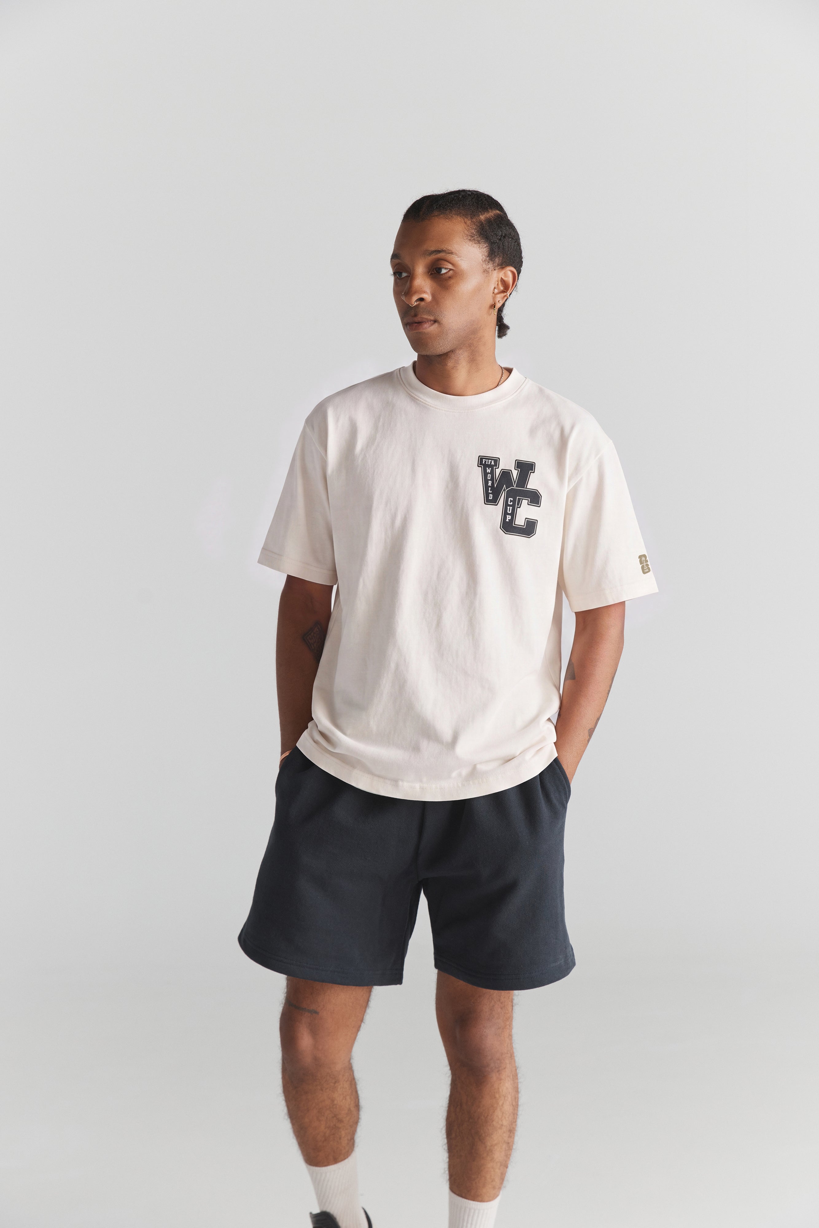 Cream FIFA World Cup graphic tee with vintage college style, paired with dark shorts. Class Trip | Higher Education