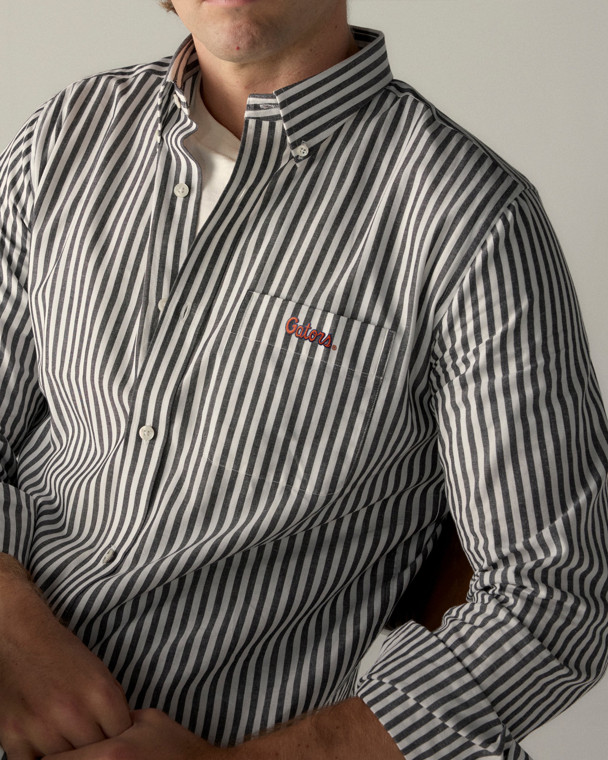 Men's black and white striped button-up shirt with Gators logo on pocket, collegiate style. Class Trip | Officially Licensed Collegiate Apparel