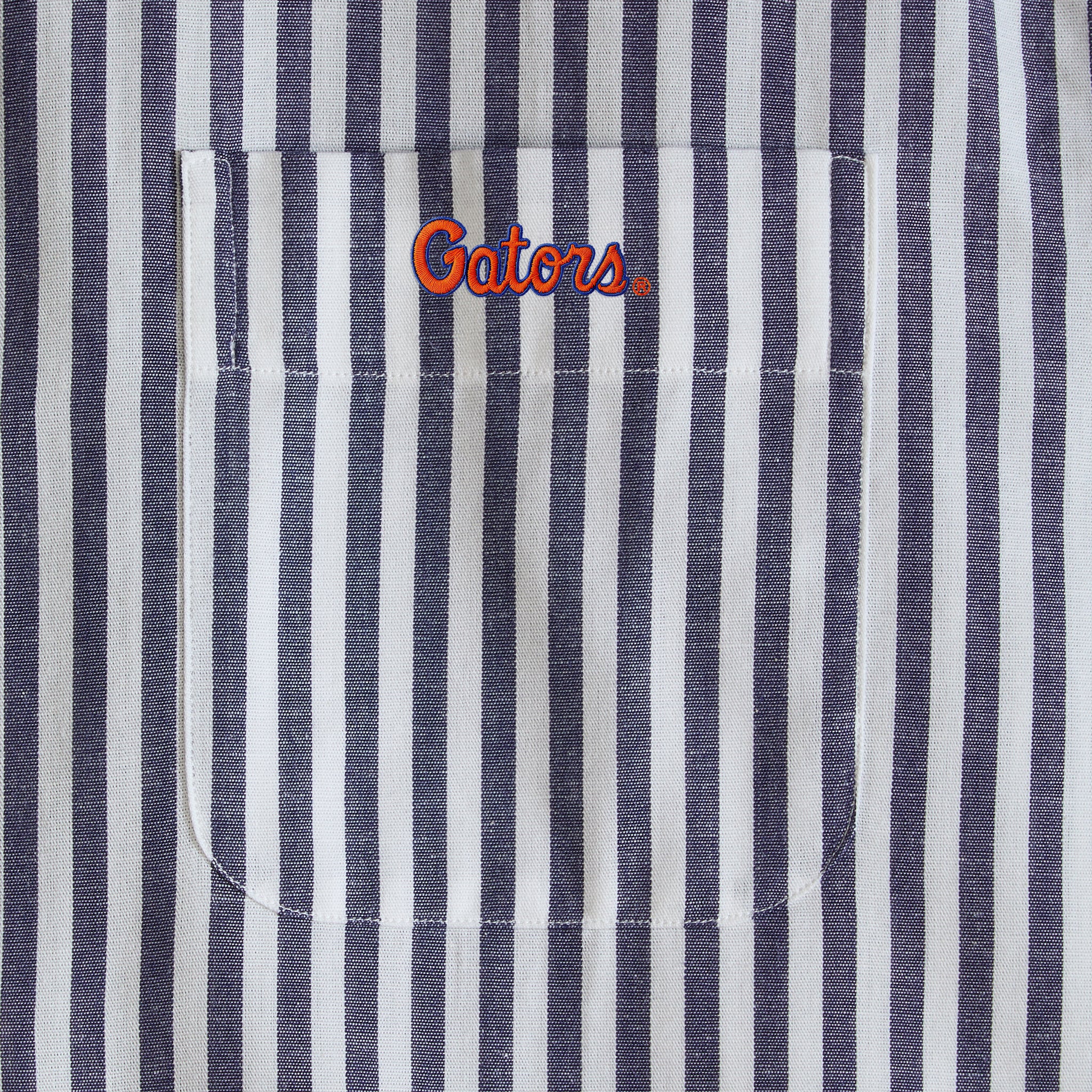 Navy and white striped men's shirt pocket with Gators logo embroidery. Class Trip | Officially Licensed Collegiate Apparel