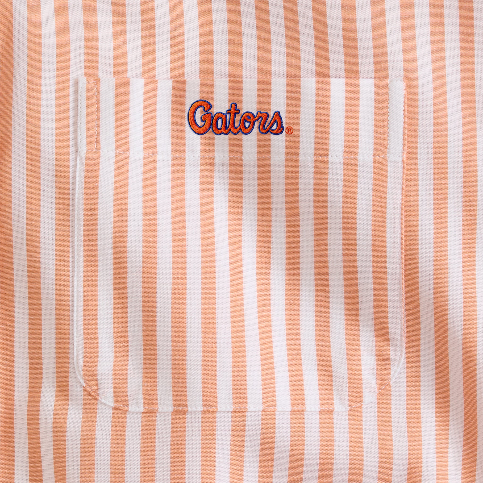 Close-up of orange and white striped men's shirt pocket with Gators embroidery. Class Trip | Officially Licensed Collegiate Apparel