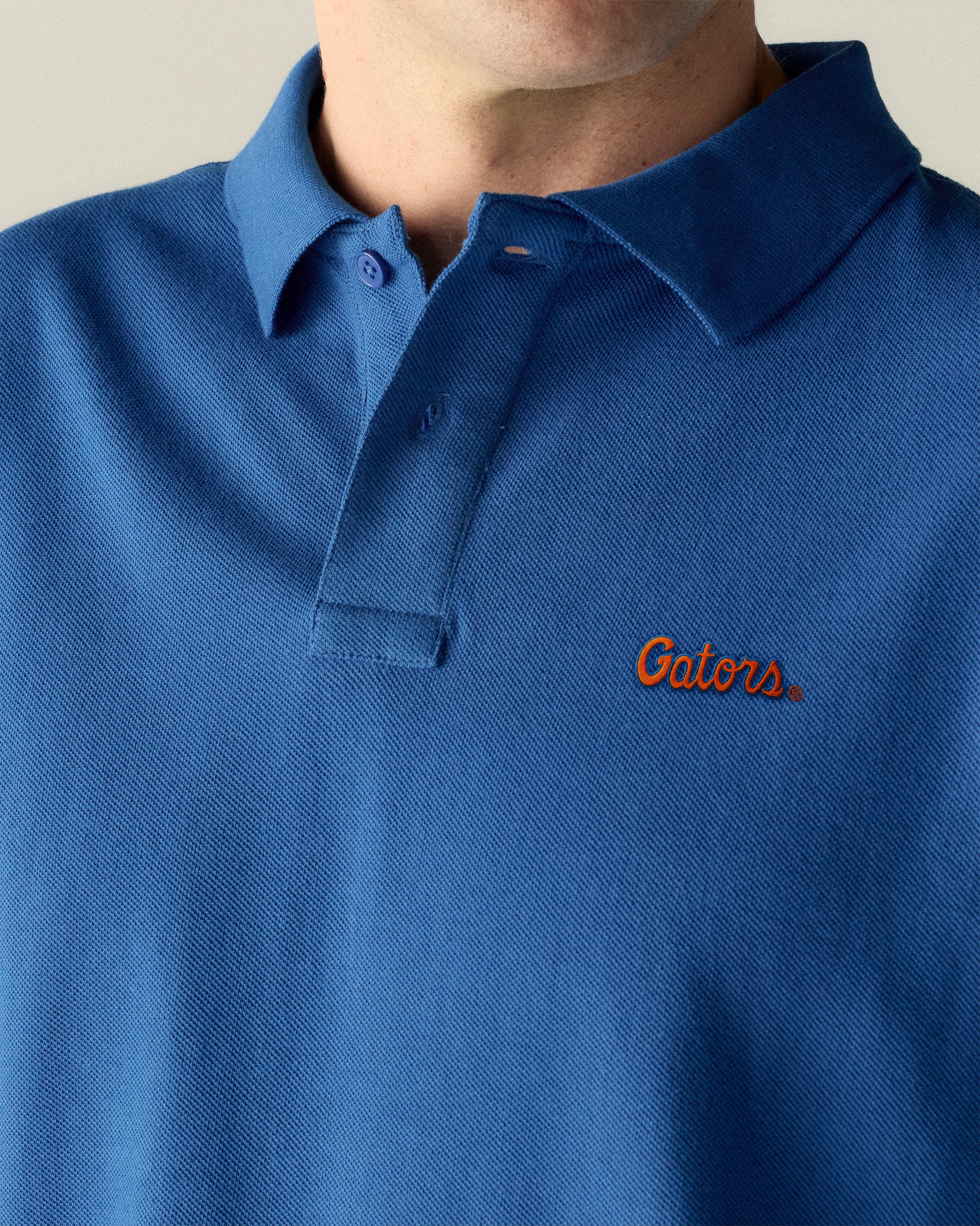Royal blue collegiate polo shirt with 'Gators' embroidered in orange on chest. Class Trip | Officially Licensed Collegiate Apparel