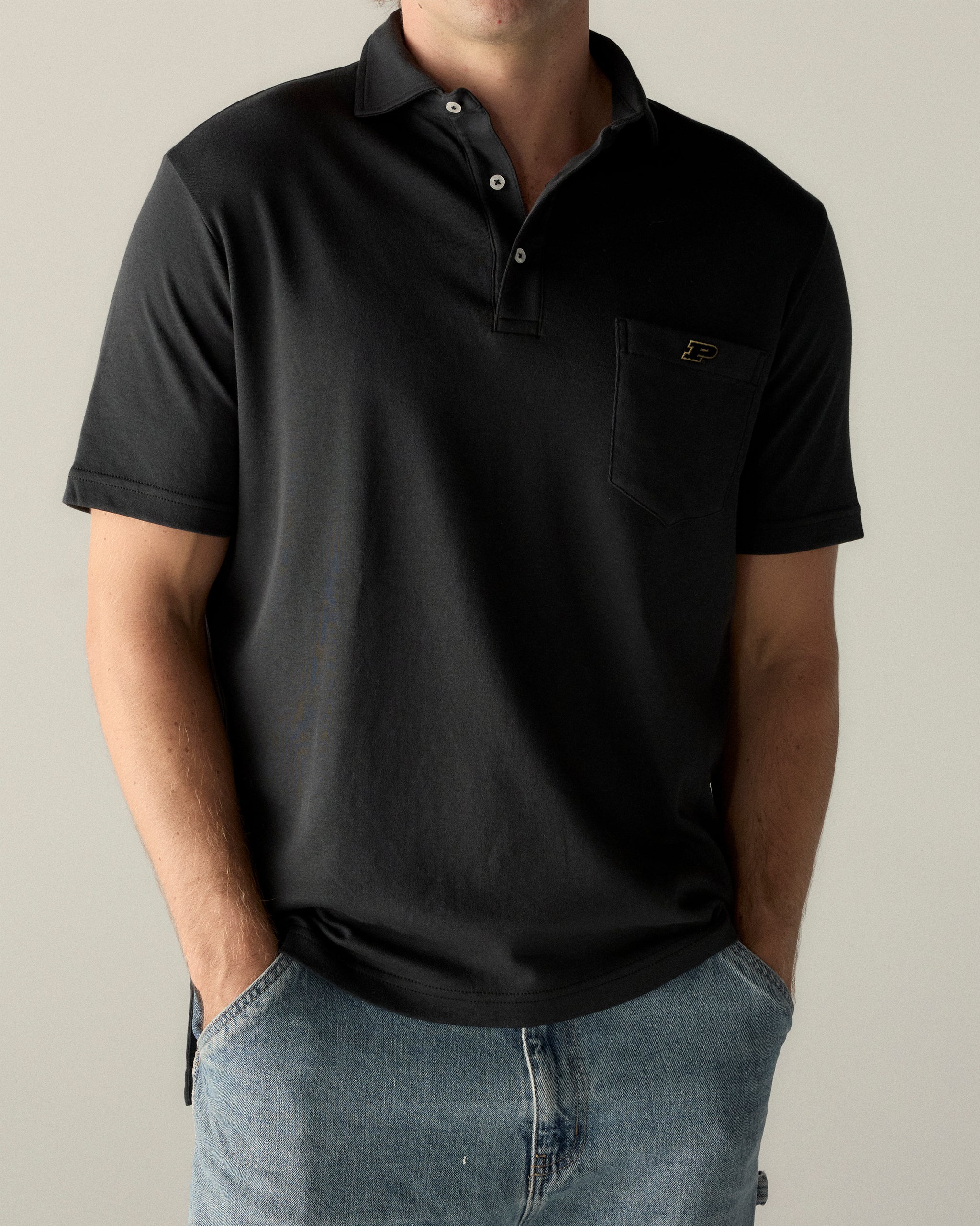 Man wearing black collegiate polo shirt with pocket and embroidered P logo, casual style. Class Trip | Officially Licensed Collegiate Apparel