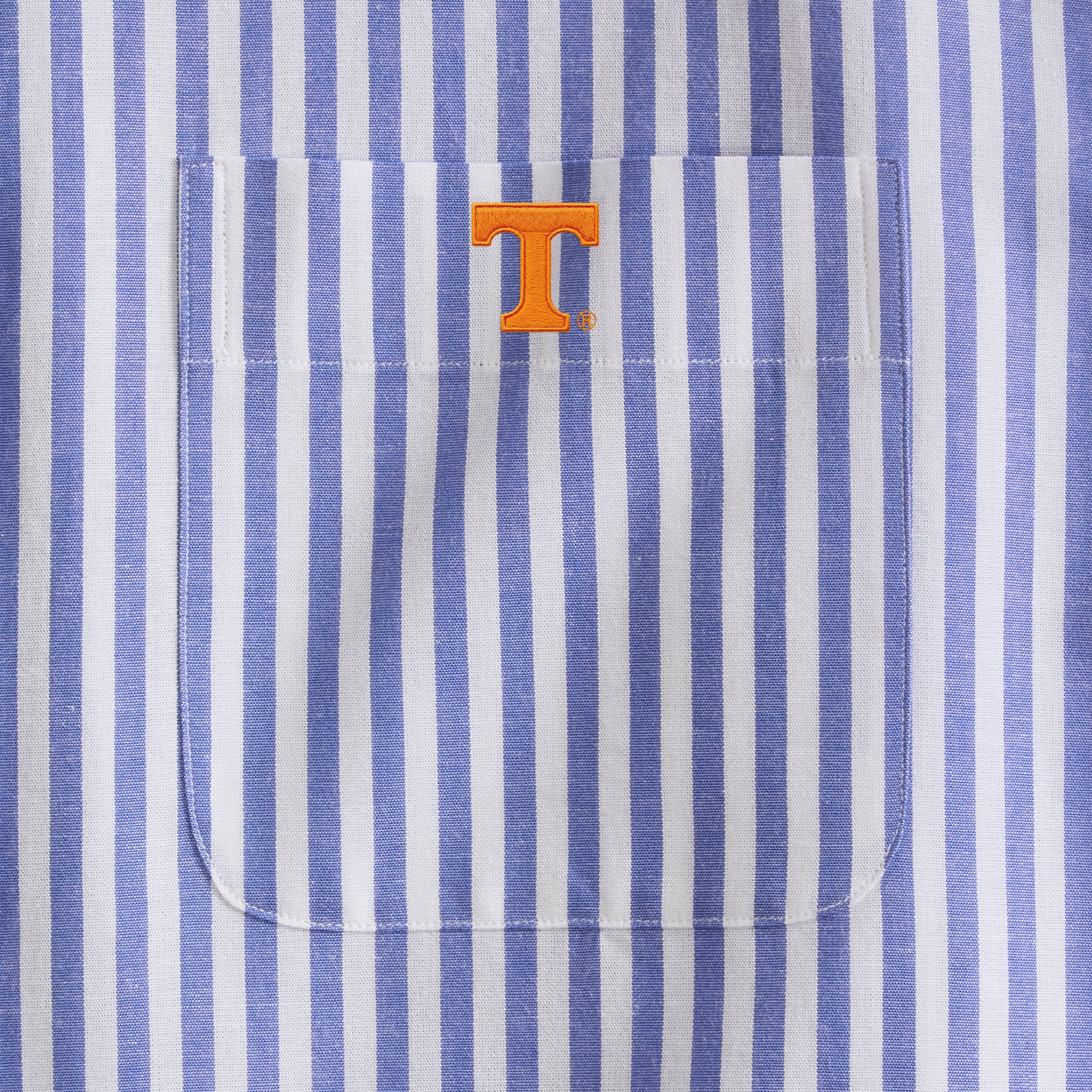 Close-up of blue and white striped men's shirt pocket with orange collegiate logo, Class Trip | Officially Licensed Collegiate Apparel