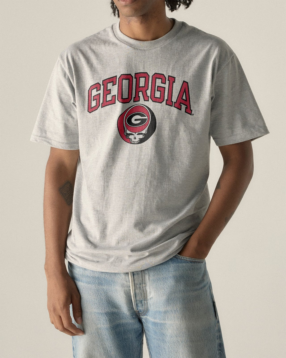Model wearing the Heather Grey Georgia x Grateful Dead Arch Steal Your Face Tee, front view. Class Trip | Higher Education