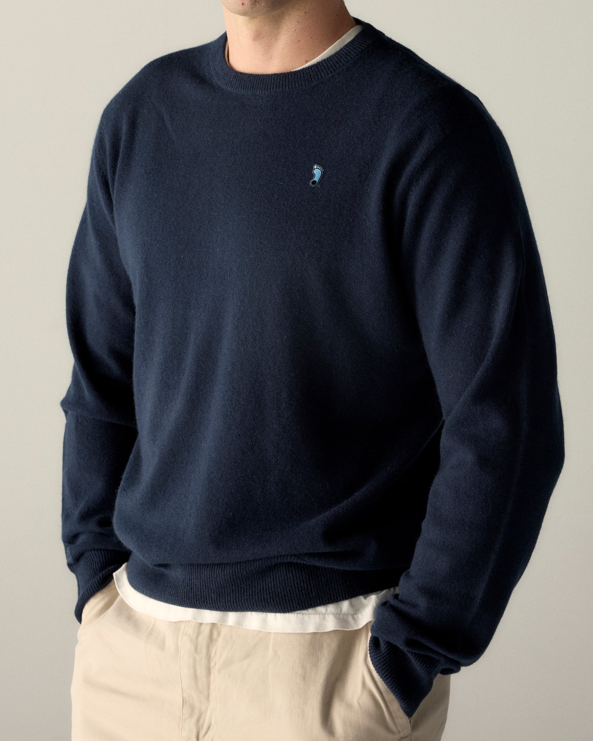 Navy crewneck sweater with small foot logo, layered over white tee. Class Trip | Officially Licensed Collegiate Apparel