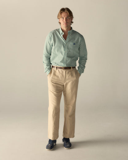 Man wearing green striped poplin shirt and beige chinos, collegiate style. Class Trip | Officially Licensed Collegiate Apparel