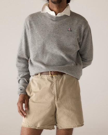 Man wearing grey merino sweater with collegiate logo and khaki shorts. Class Trip | Officially Licensed Collegiate Apparel