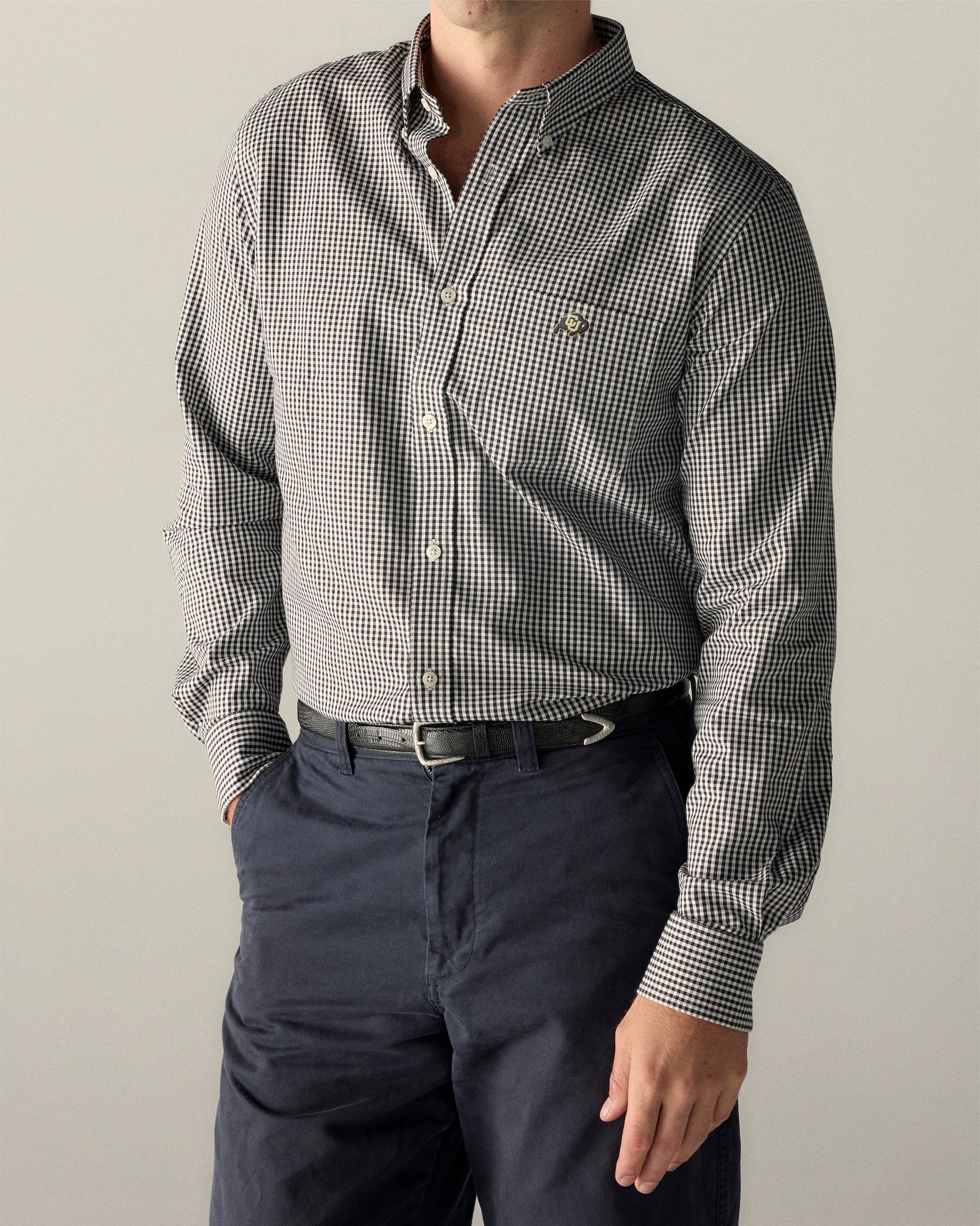 Man wearing a black checkered Oxford shirt with button-down collar and navy pants. Class Trip | Officially Licensed Collegiate Apparel