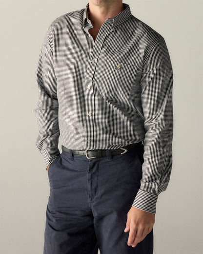 Man wearing a black checkered Oxford shirt with button-down collar and navy pants. Class Trip | Officially Licensed Collegiate Apparel