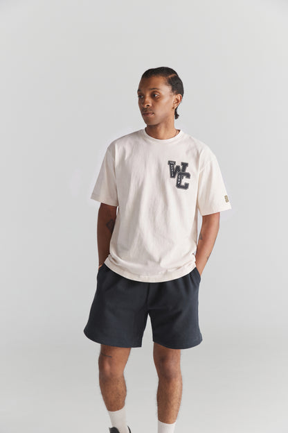 Cream FIFA World Cup graphic tee with vintage college style, paired with dark shorts. Class Trip | Higher Education
