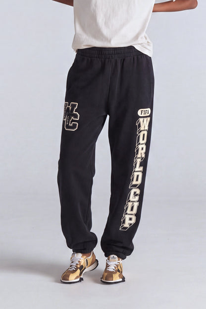 Black FIFA World Cup sweatpants with gold lettering, paired with gold sneakers. Class Trip | Higher Education