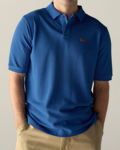 Man wearing royal blue collegiate polo shirt with 'Gators' chest logo, khaki pants. Class Trip | Officially Licensed Collegiate Apparel