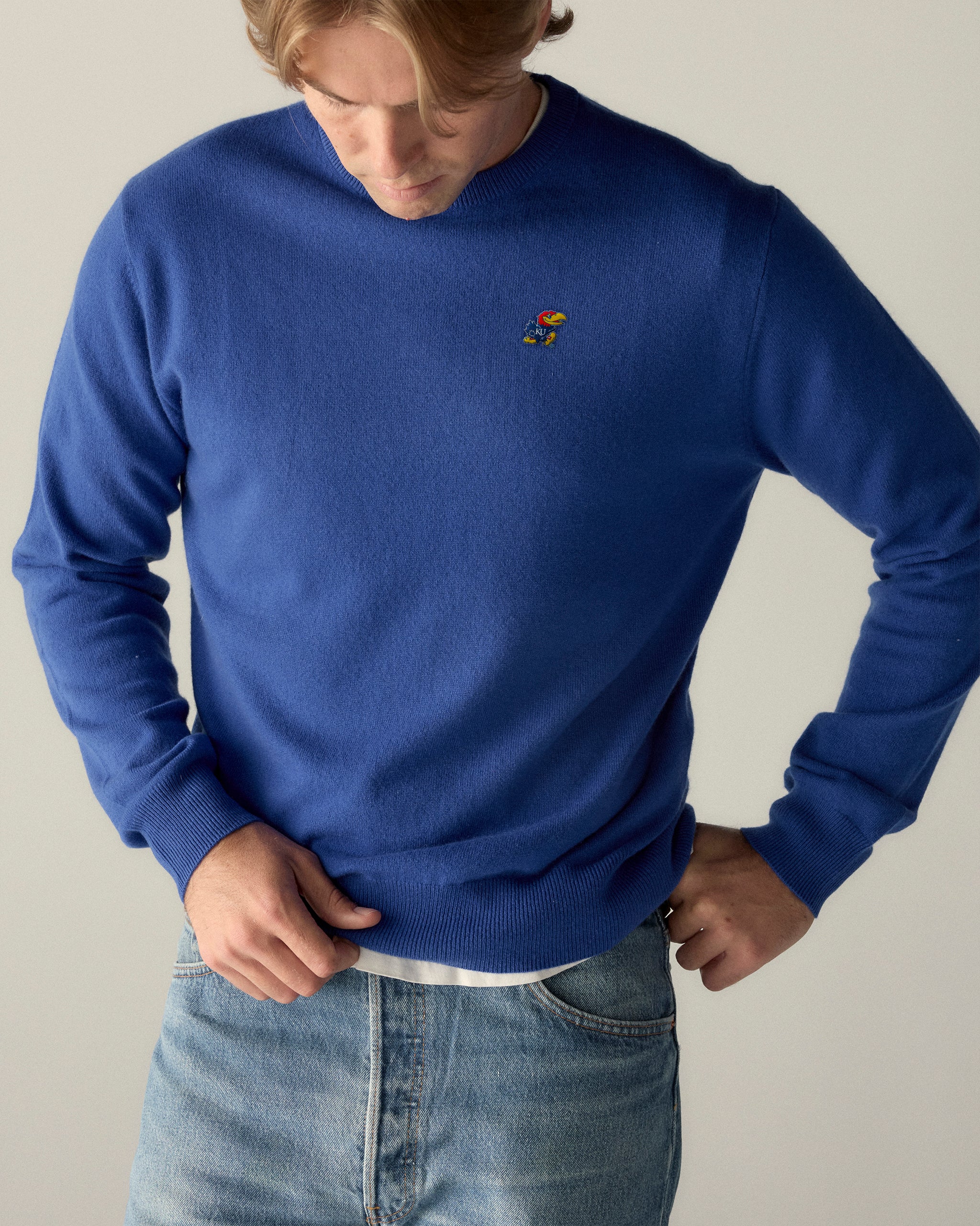 Royal blue crewneck sweater with embroidered Jayhawk logo, worn with jeans. Kansas KU apparel. Class Trip | Officially Licensed Collegiate Apparel