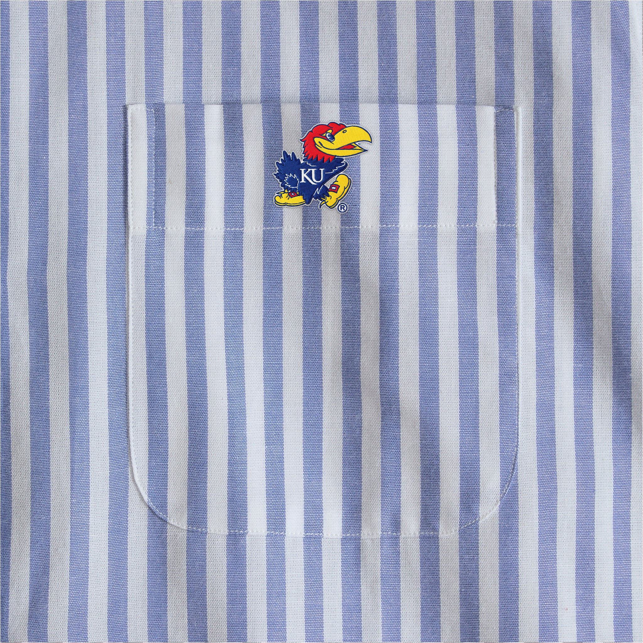 Blue and white striped shirt pocket with KU Jayhawk logo, collegiate apparel detail. Class Trip | Officially Licensed Collegiate Apparel