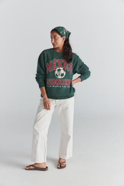 Green Mexico Soccer sweatshirt with FIFA World Cup 2026 graphic, worn with white pants and bandana. Class Trip | Higher Education