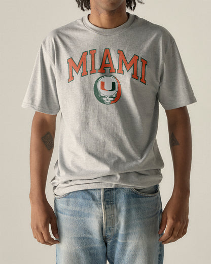 Man wearing a grey University of Miami x Grateful Dead Steal Your Face Arch Tee. Class Trip | Higher Education