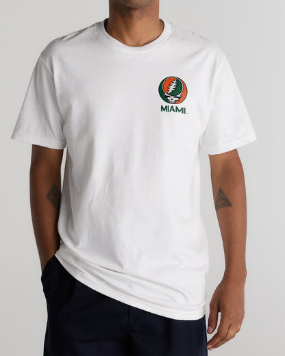 A person wearing a white Class Trip t-shirt featuring a University of Miami x Grateful Dead logo. University of Miami x Grateful Dead Shakedown Tee Class Trip | Higher Education