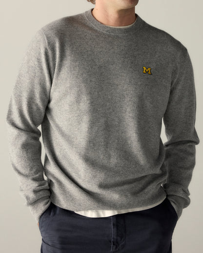 Man wearing grey collegiate crewneck sweater with yellow M logo, casual style. Class Trip | Officially Licensed Collegiate Apparel