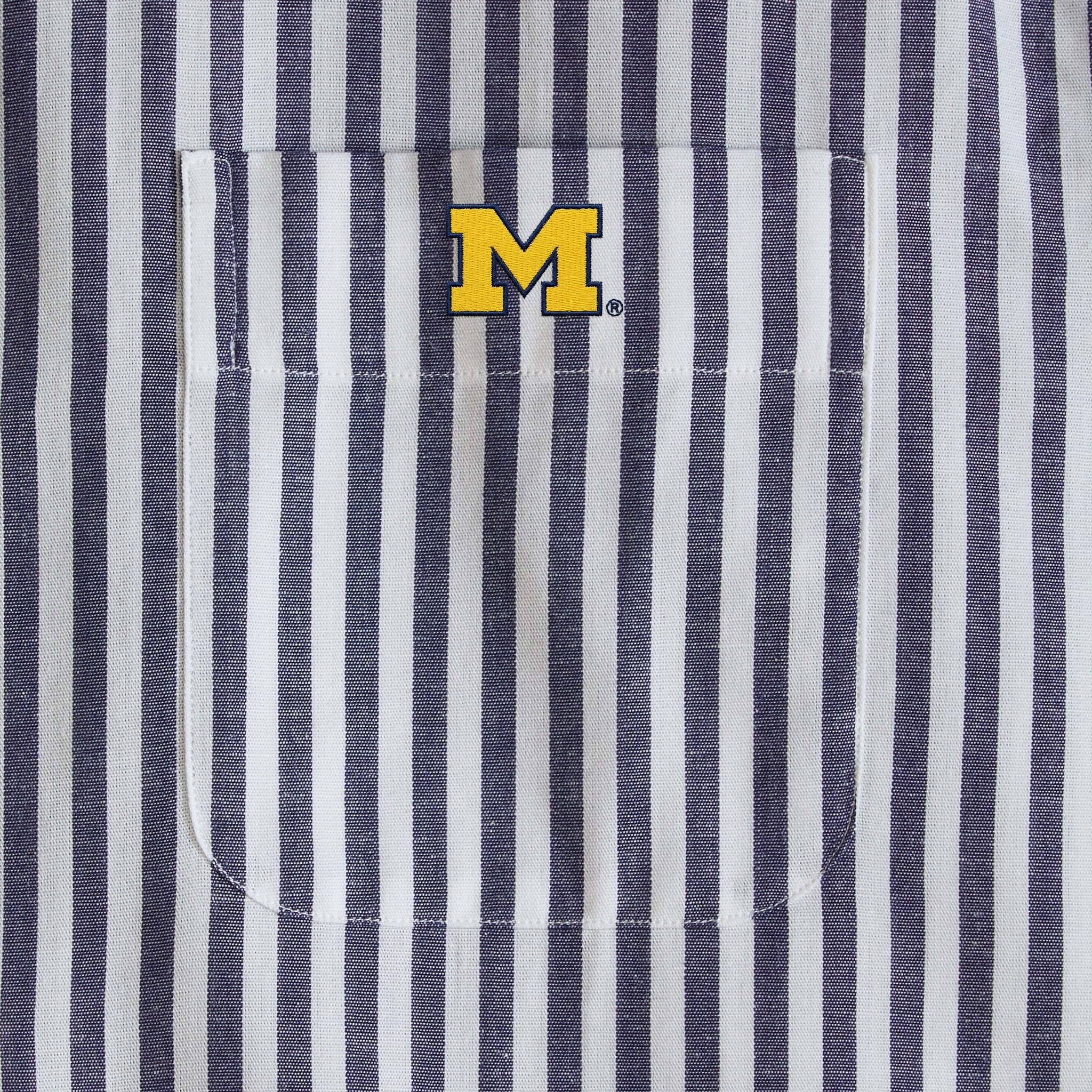 Navy and white striped men's shirt pocket with yellow collegiate M logo. Class Trip | Officially Licensed Collegiate Apparel