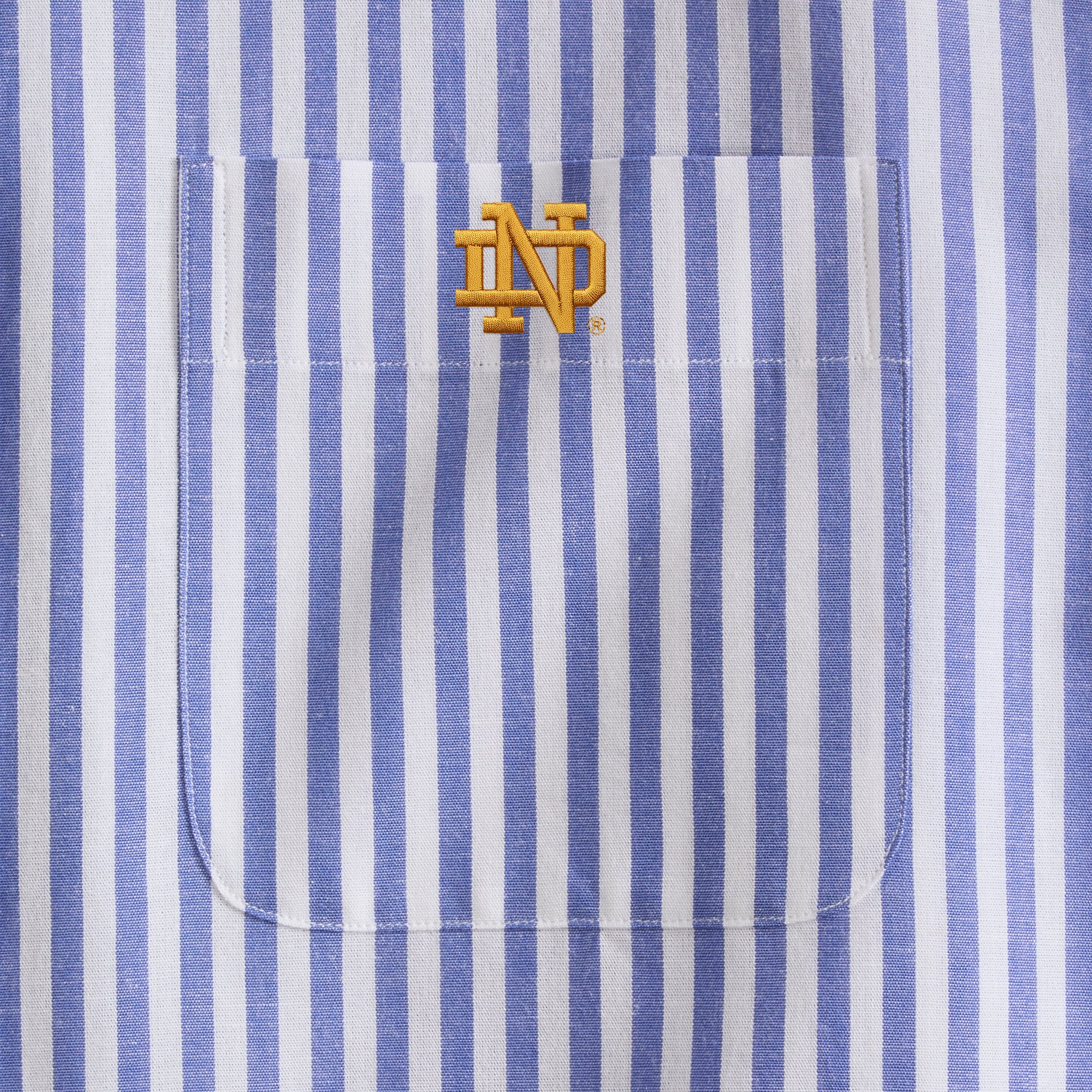 Blue and white striped poplin shirt pocket with yellow embroidered collegiate logo. Class Trip | Officially Licensed Collegiate Apparel