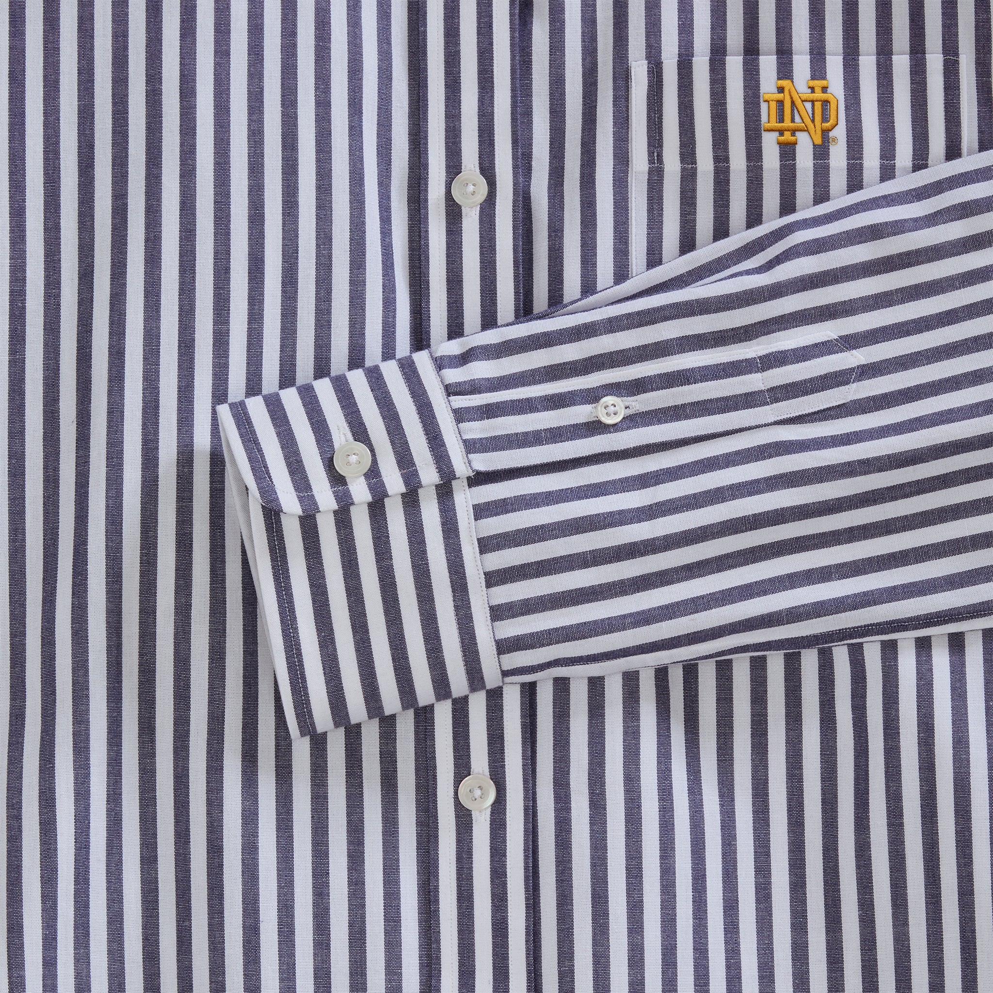 Close-up of navy and white striped poplin shirt with embroidered collegiate logo, button cuffs | Class Trip | Officially Licensed Collegiate Apparel