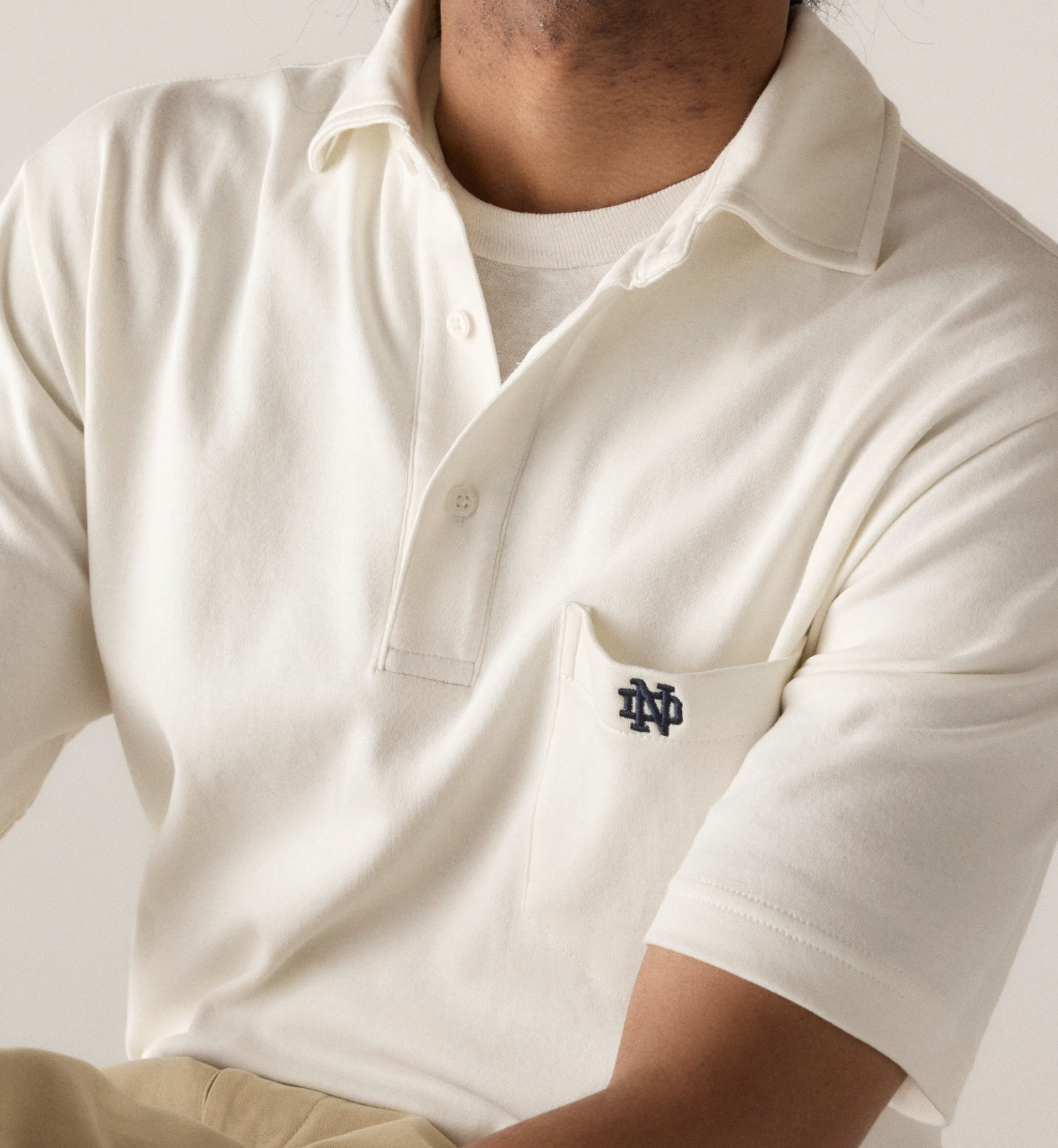 Man wearing a white pocket polo with Notre Dame University logo.