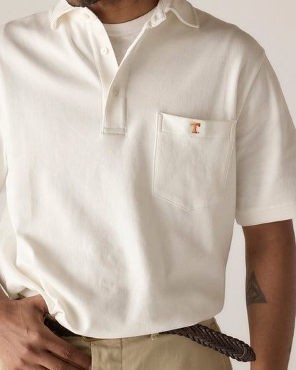 White collegiate polo shirt with pocket and orange T logo, worn with khaki pants. Class Trip | Officially Licensed Collegiate Apparel